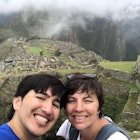 A man and a woman pose for the camera with the Inca ruins of Machu Picchu in the background.
